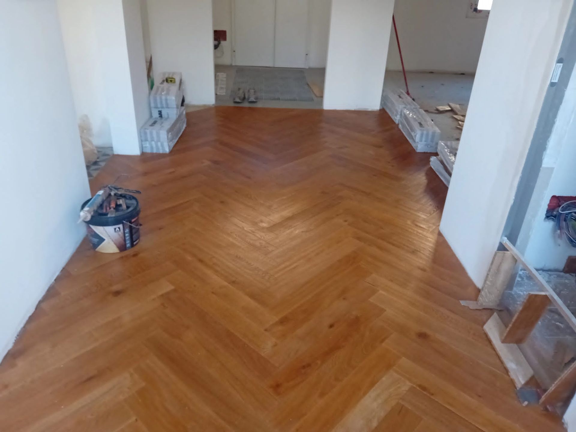 Pavimento in legno massello a spina di pesce appena installato in una stanza con pareti bianche
