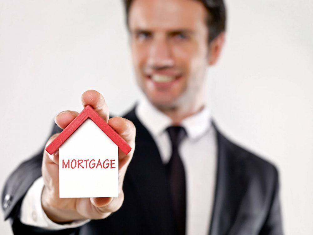 Man in Suit Smiling, Holding a Small House — Into Finance Lending Solutions in Nabiac, NSW
