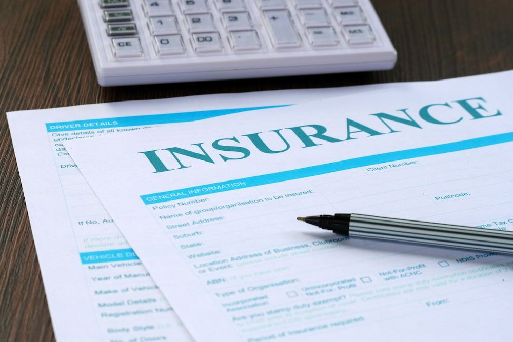 Insurance Form With a Pen and a Calculator on a Wooden Surface — Into Finance Lending Solutions in Tuncurry, NSW