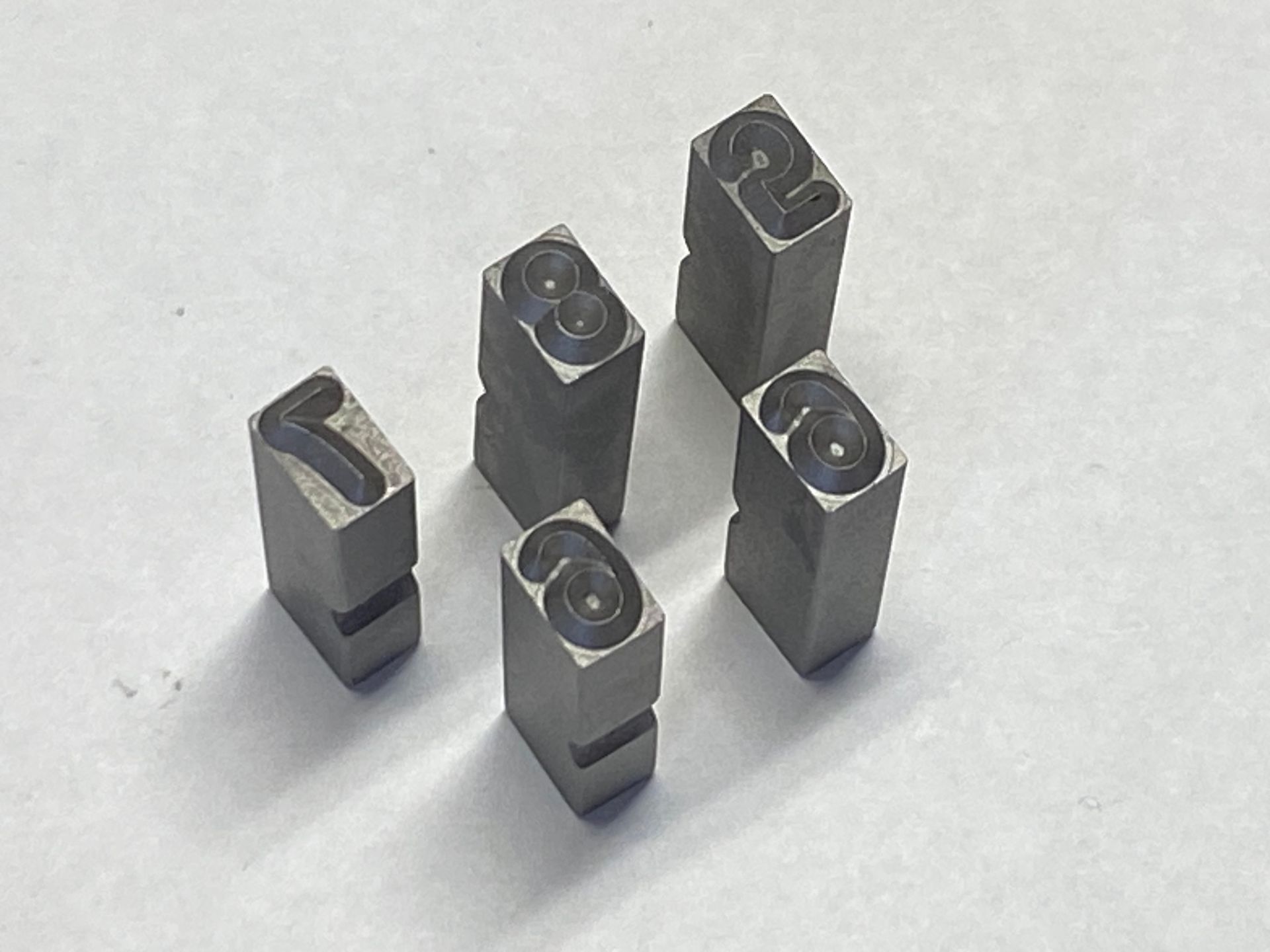 Two cylindrical metal parts, one with Chevrolet logo and hole, the other with a hole.