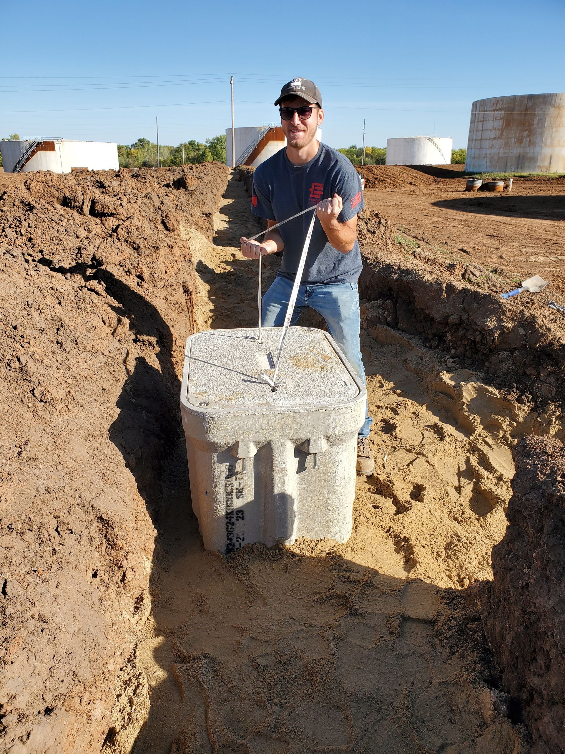 A man is pushing a concrete block in the dirt