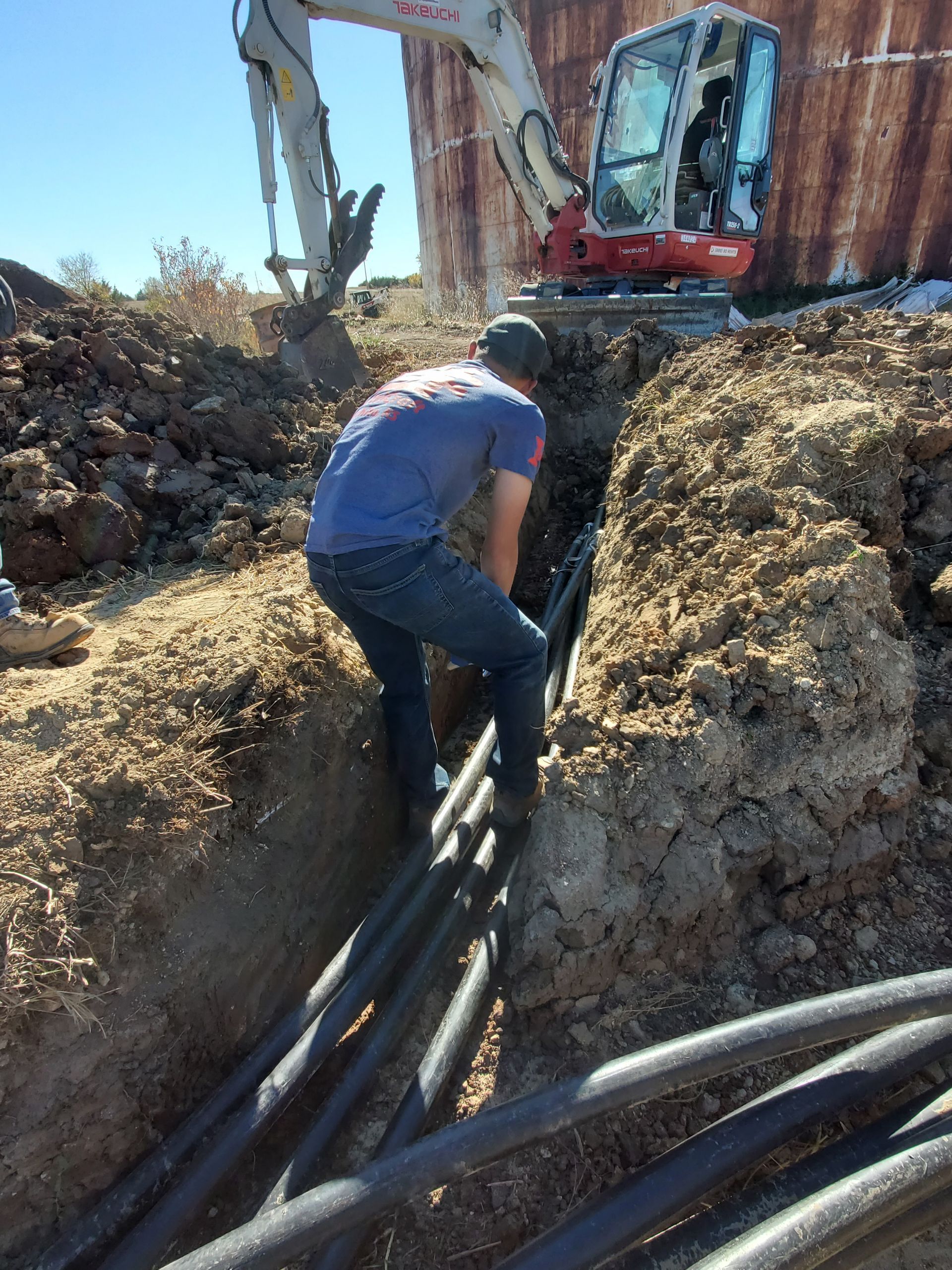 A man in a blue shirt is digging a hole in the ground