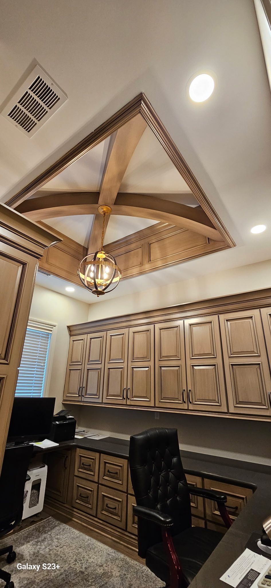 A kitchen with a ceiling fan and a desk and chair.