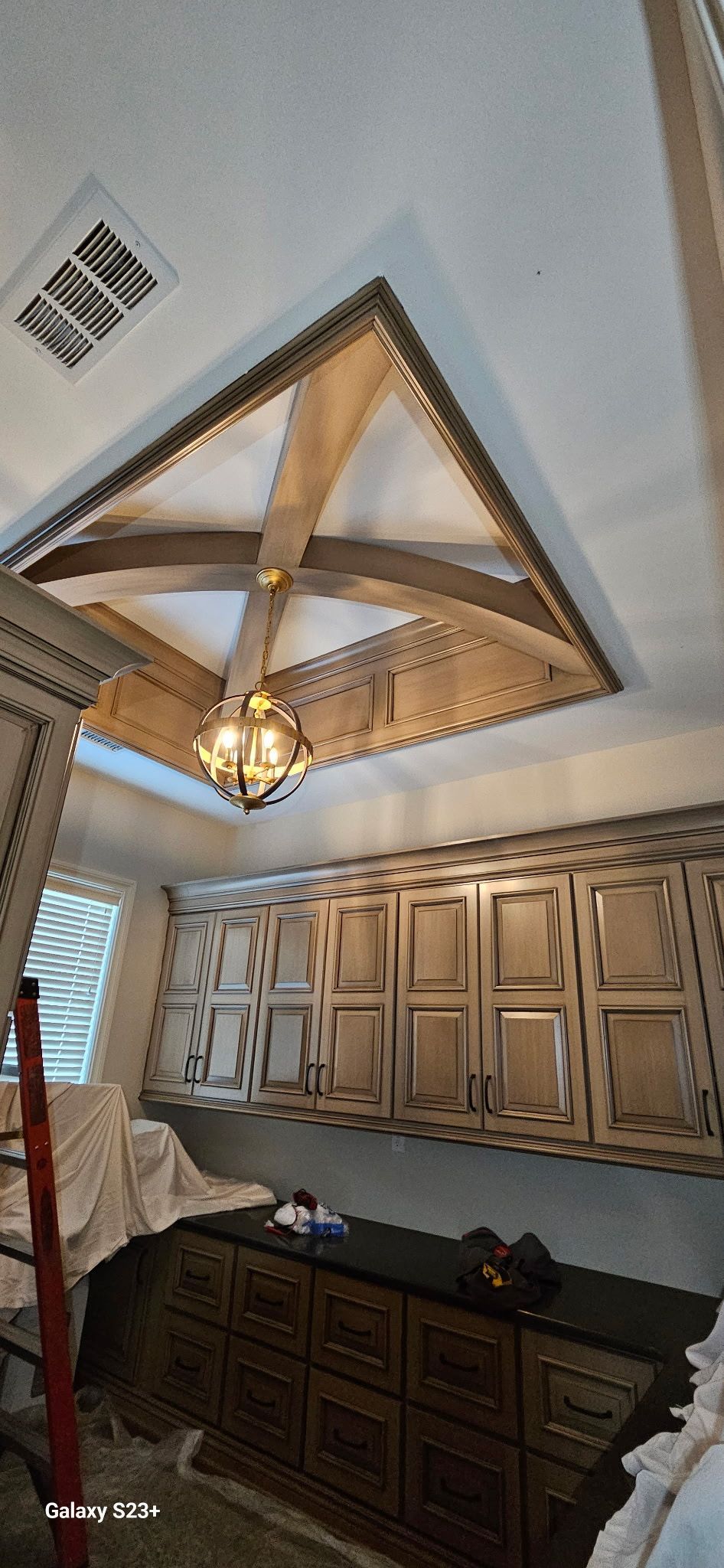 A kitchen under construction with a chandelier hanging from the ceiling.