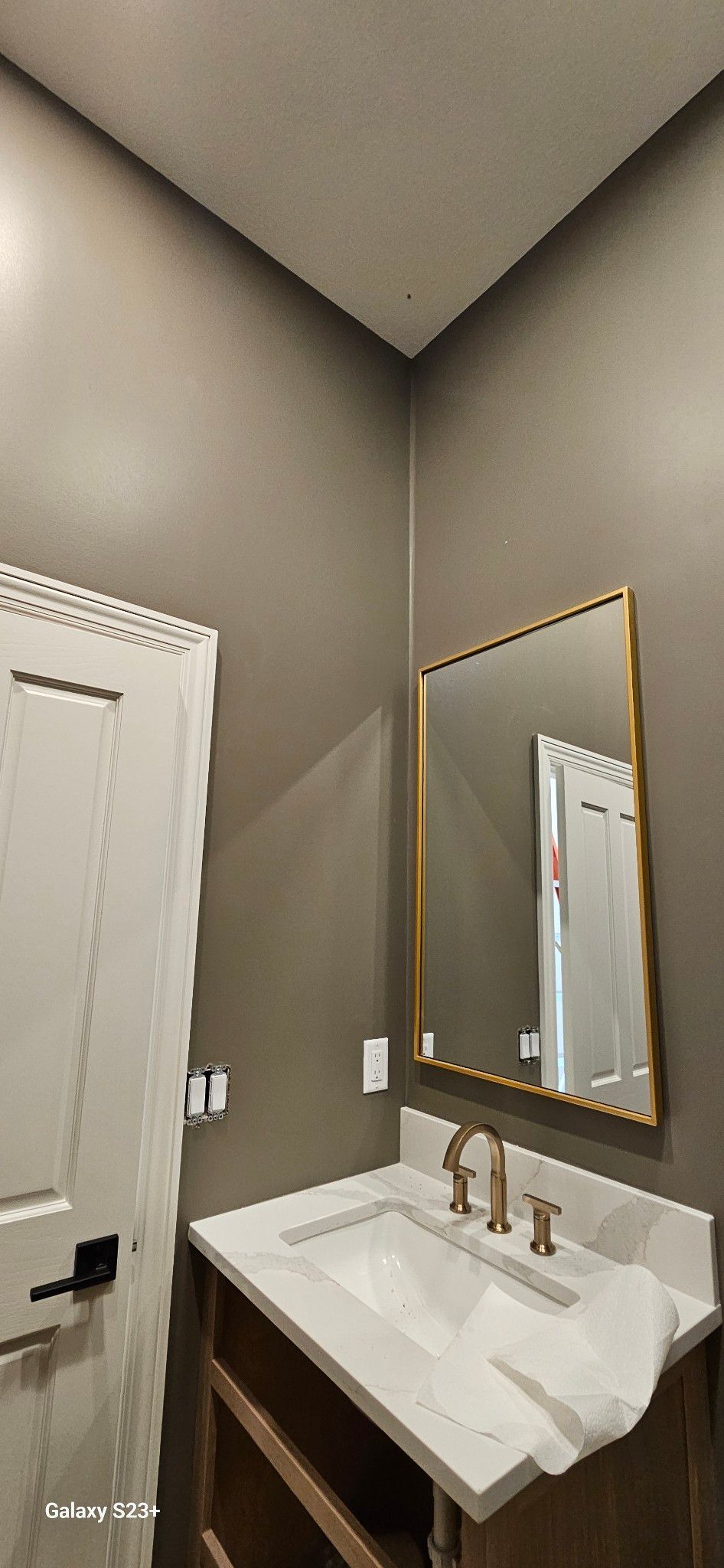 Bathroom with white sink, gold-framed mirror, and door.