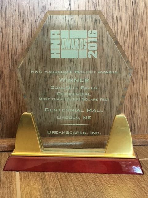 Clear award plaque trophy on a wooden surface with gold base and red accent