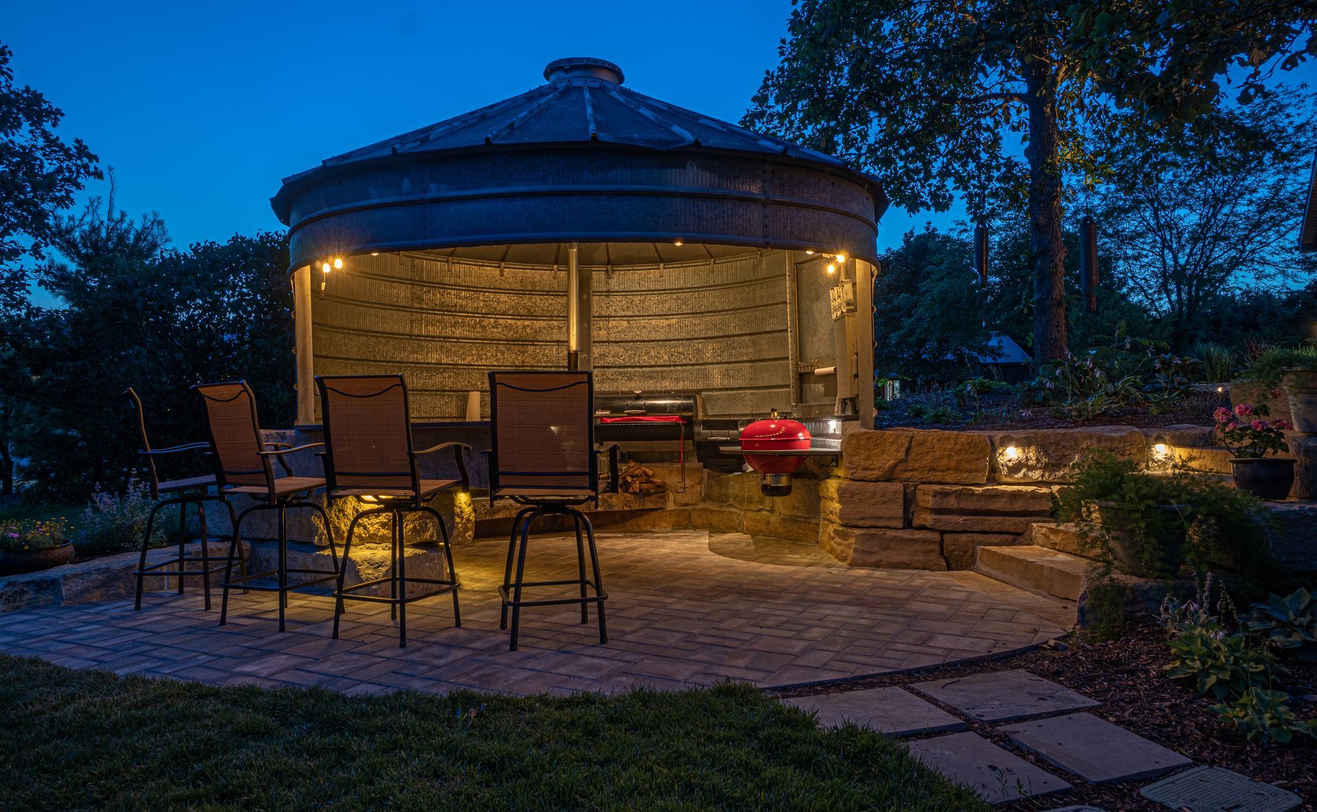 Outdoor patio with lit circular gazebo, chairs, and a table at dusk