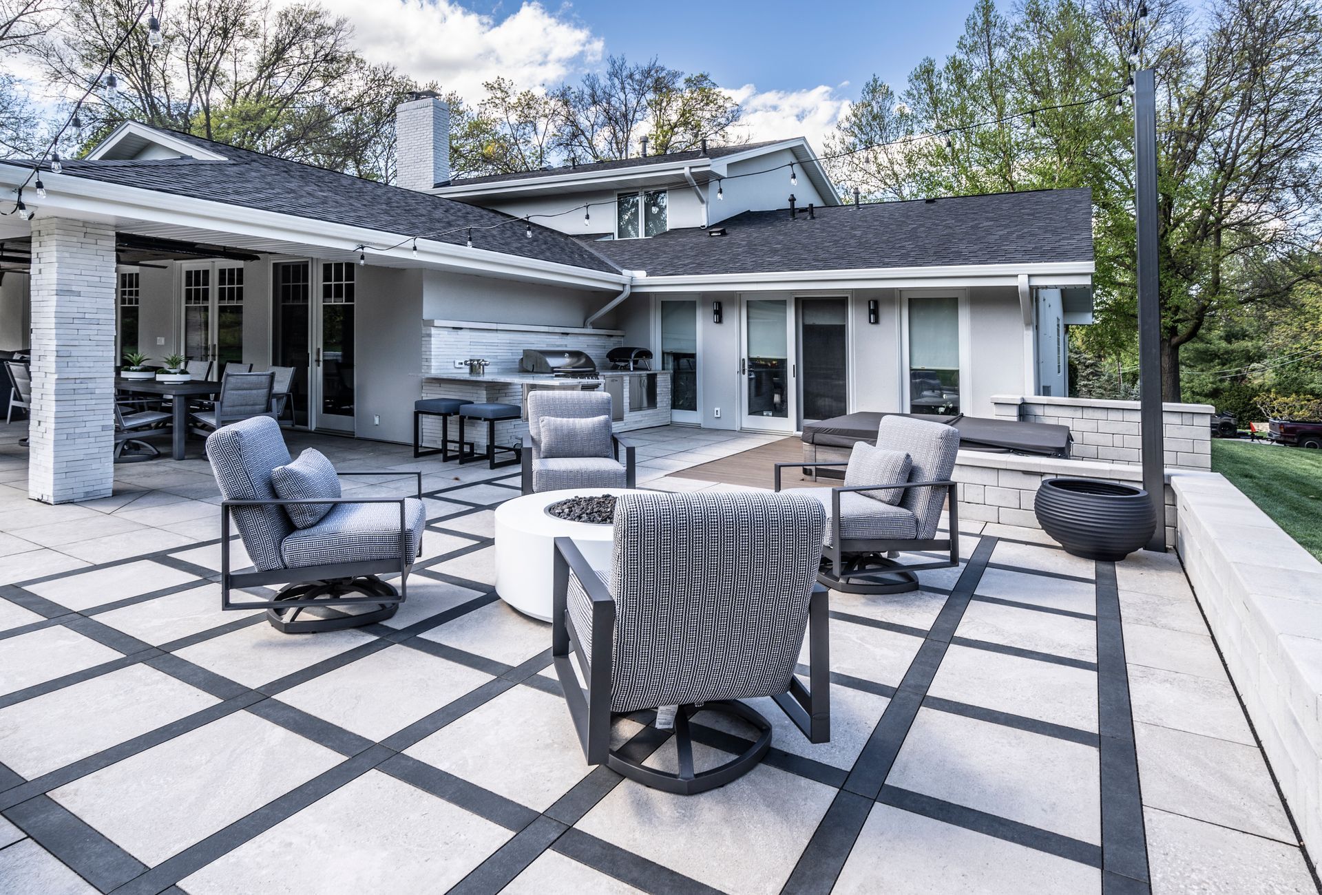 Modern patio with gray outdoor seating and fire table on a black-and-white tiled deck