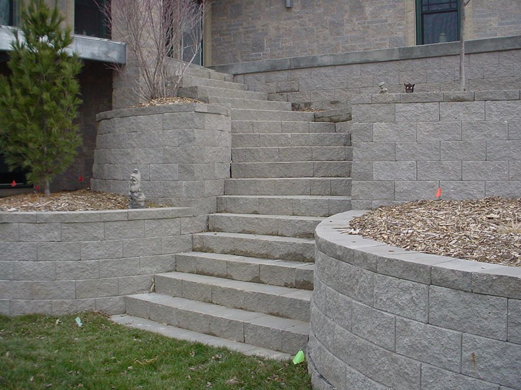 Stone outdoor stairs between retaining walls and a grassy yard.