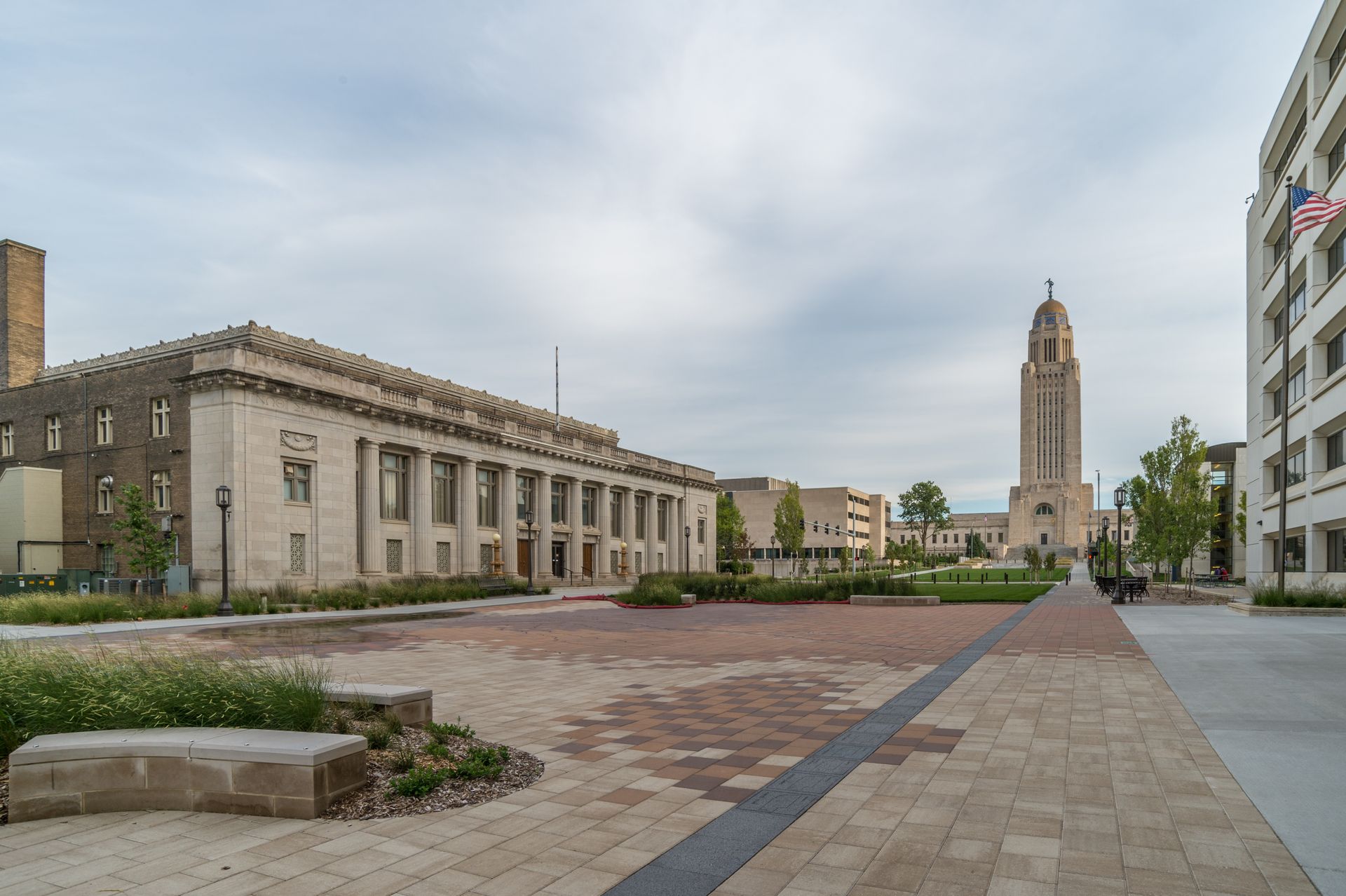 Wide plaza with stone buildings and a tall clock tower under an overcast sky