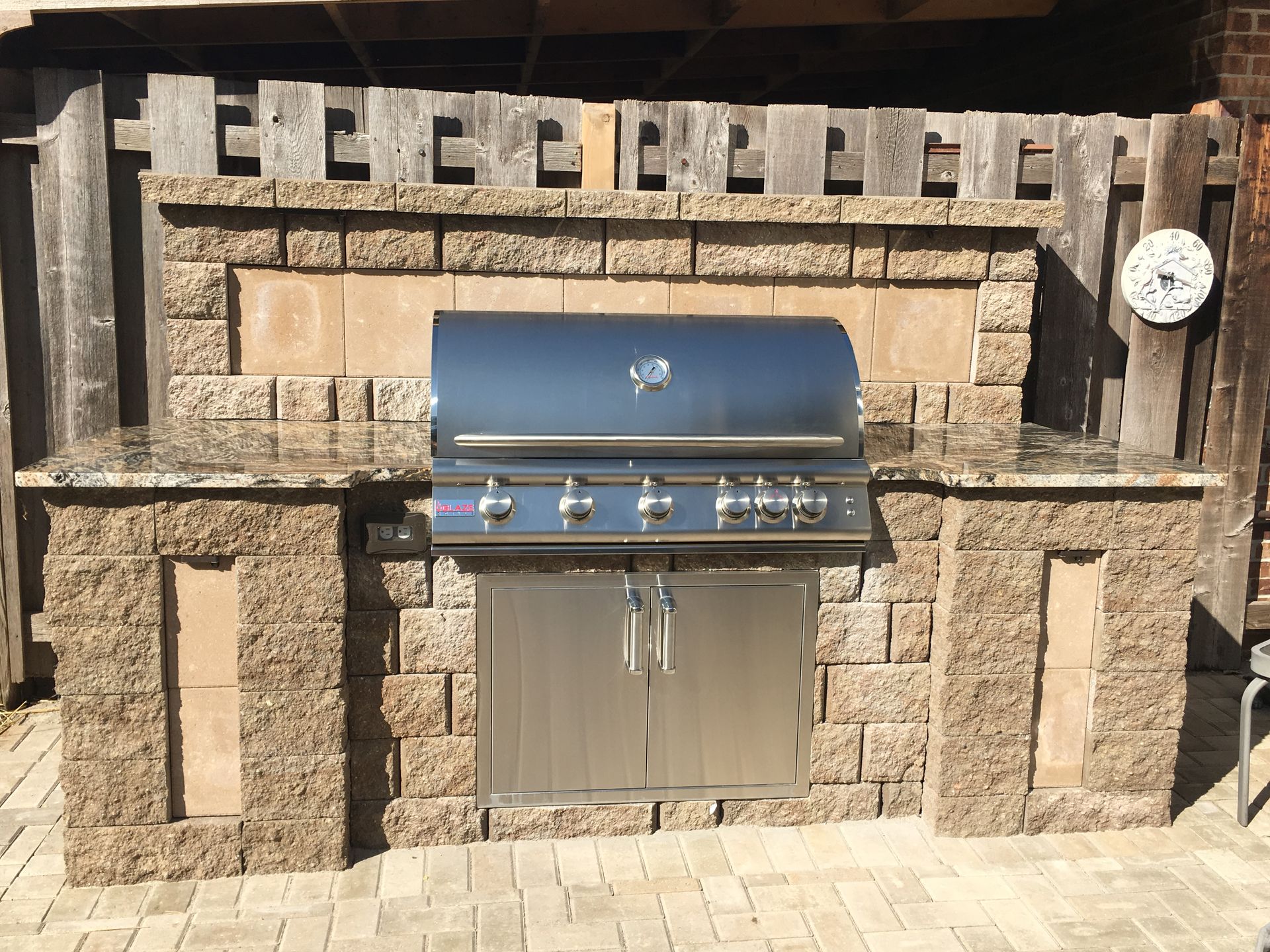 Built-in stainless steel grill in a brick outdoor kitchen alcove