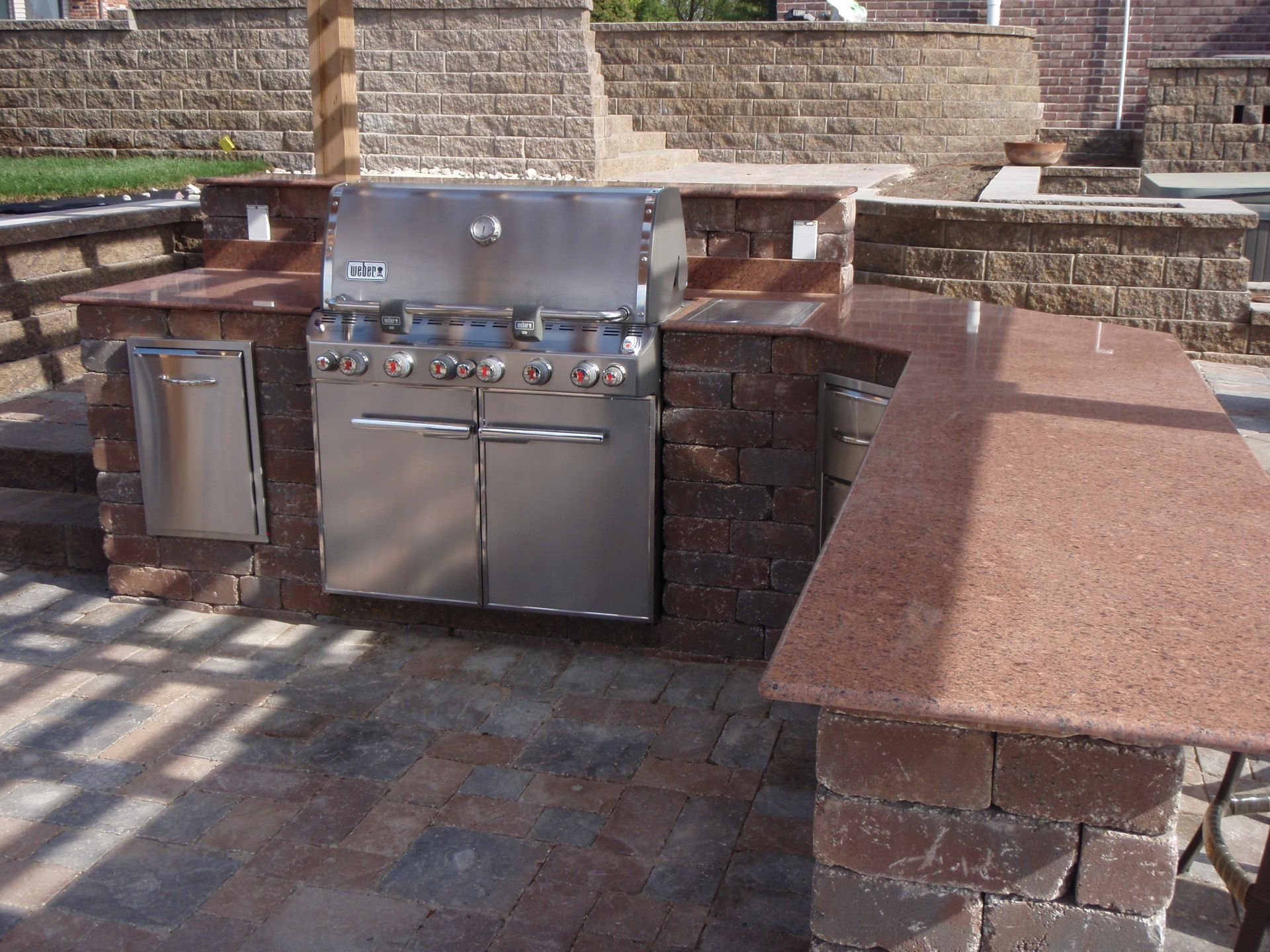 Outdoor brick patio with built-in stainless steel grill and countertop seating area