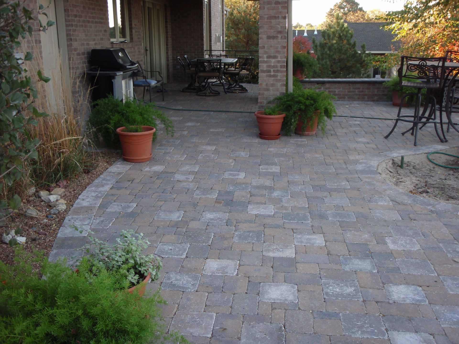 Patio with brick pavers, potted plants, and outdoor seating under a covered terrace