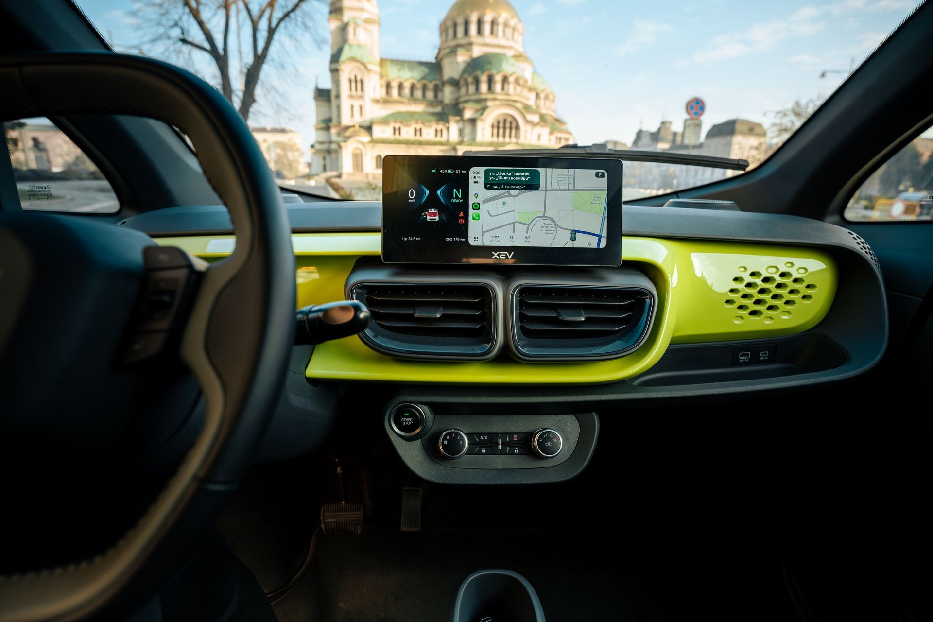 Car dashboard with GPS screen, yellow trim, and a view of a domed building outside the windshield