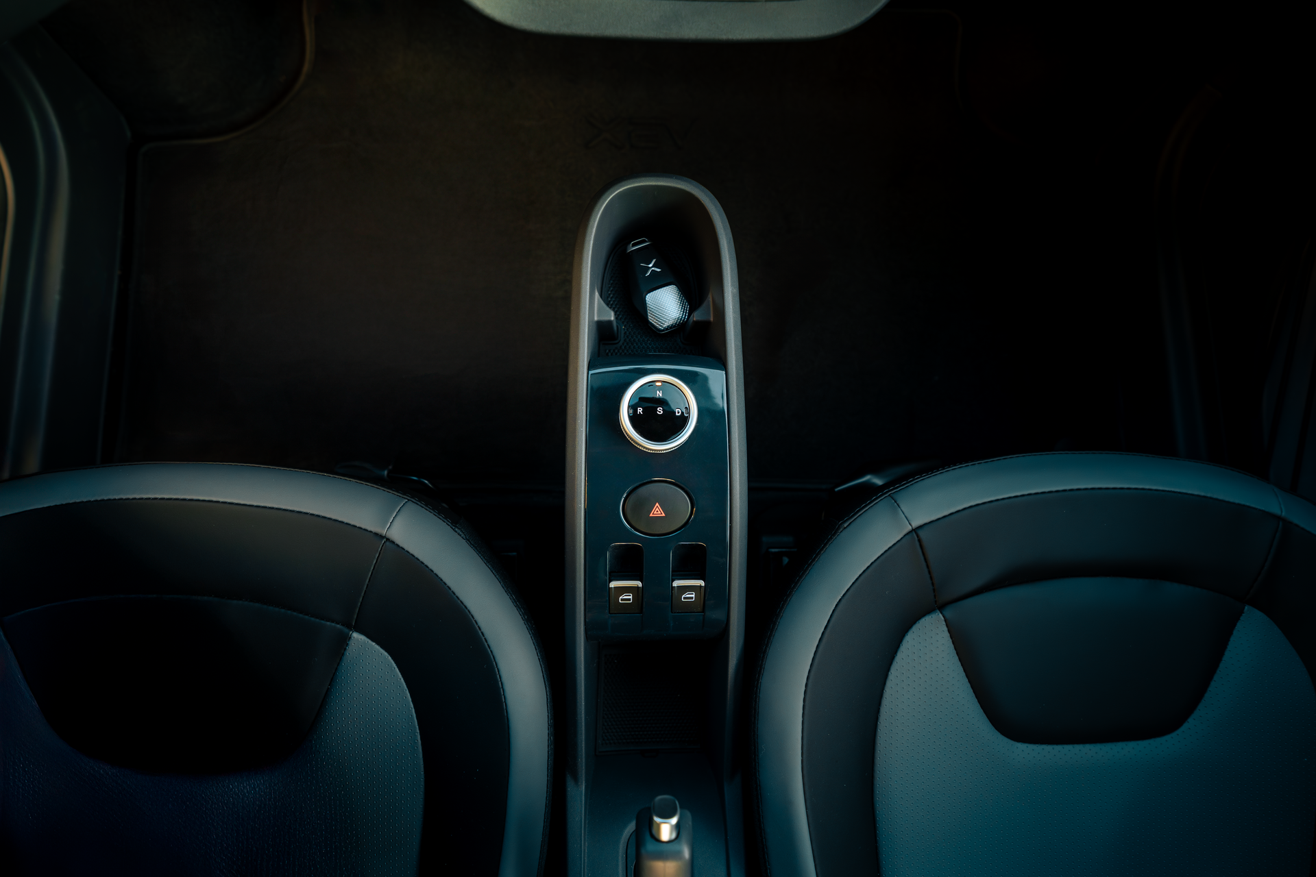 Car interior with two front seats and a central control panel in dark blue lighting
