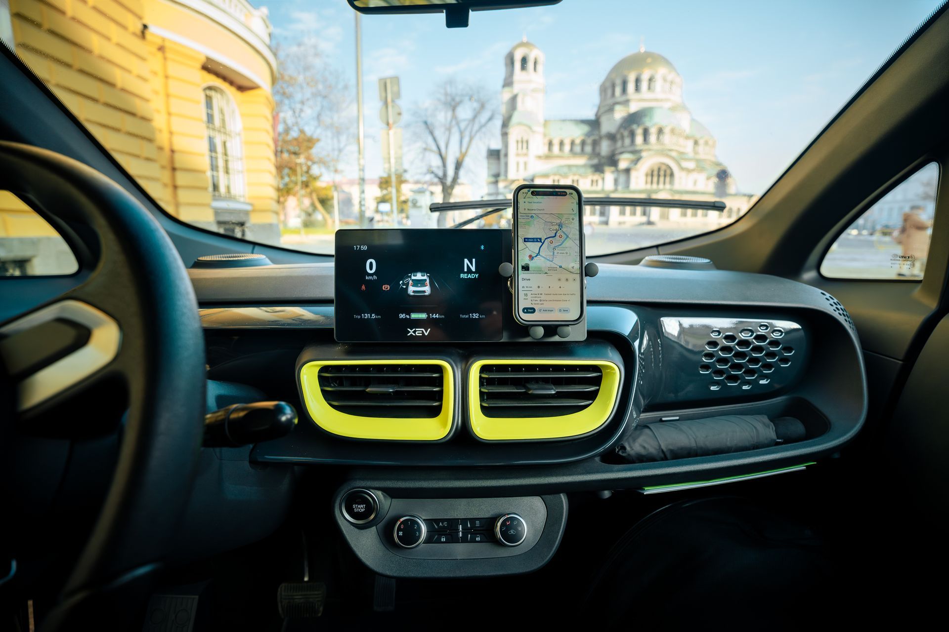 Car dashboard view with phone mount, display screen, and cathedral seen through the windshield