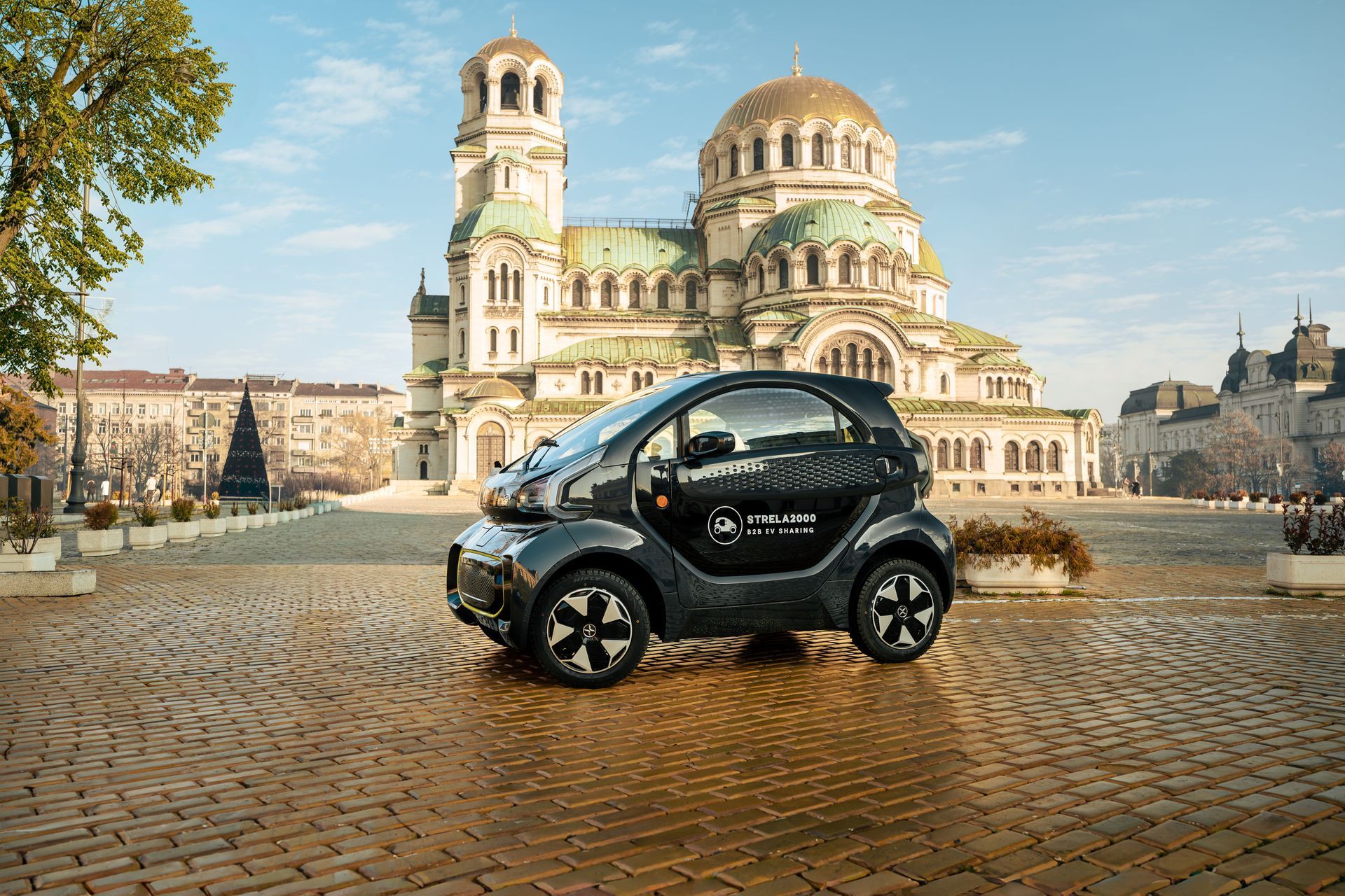Black compact car on a cobblestone square with a cathedral in the background.