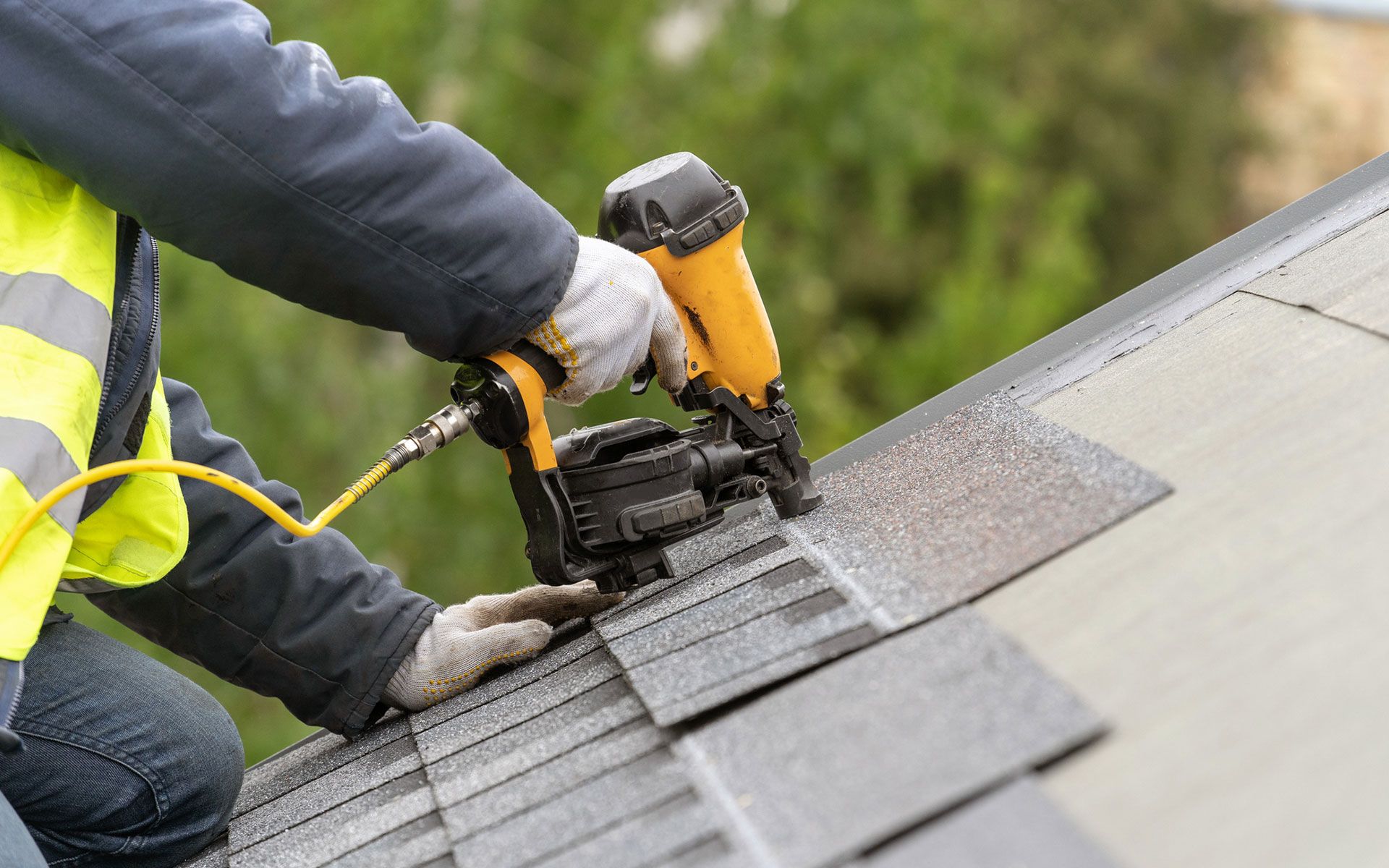 A man is cleaning a wooden deck with a high pressure washer.