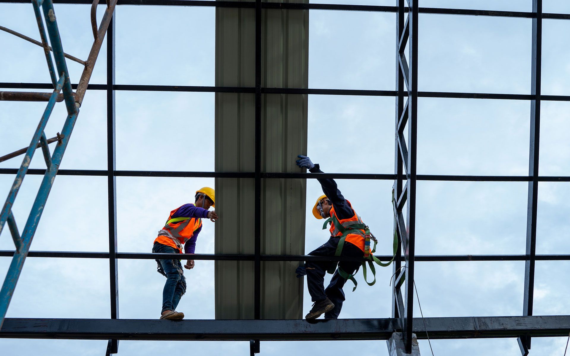 Two construction workers are working on the side of a building.
