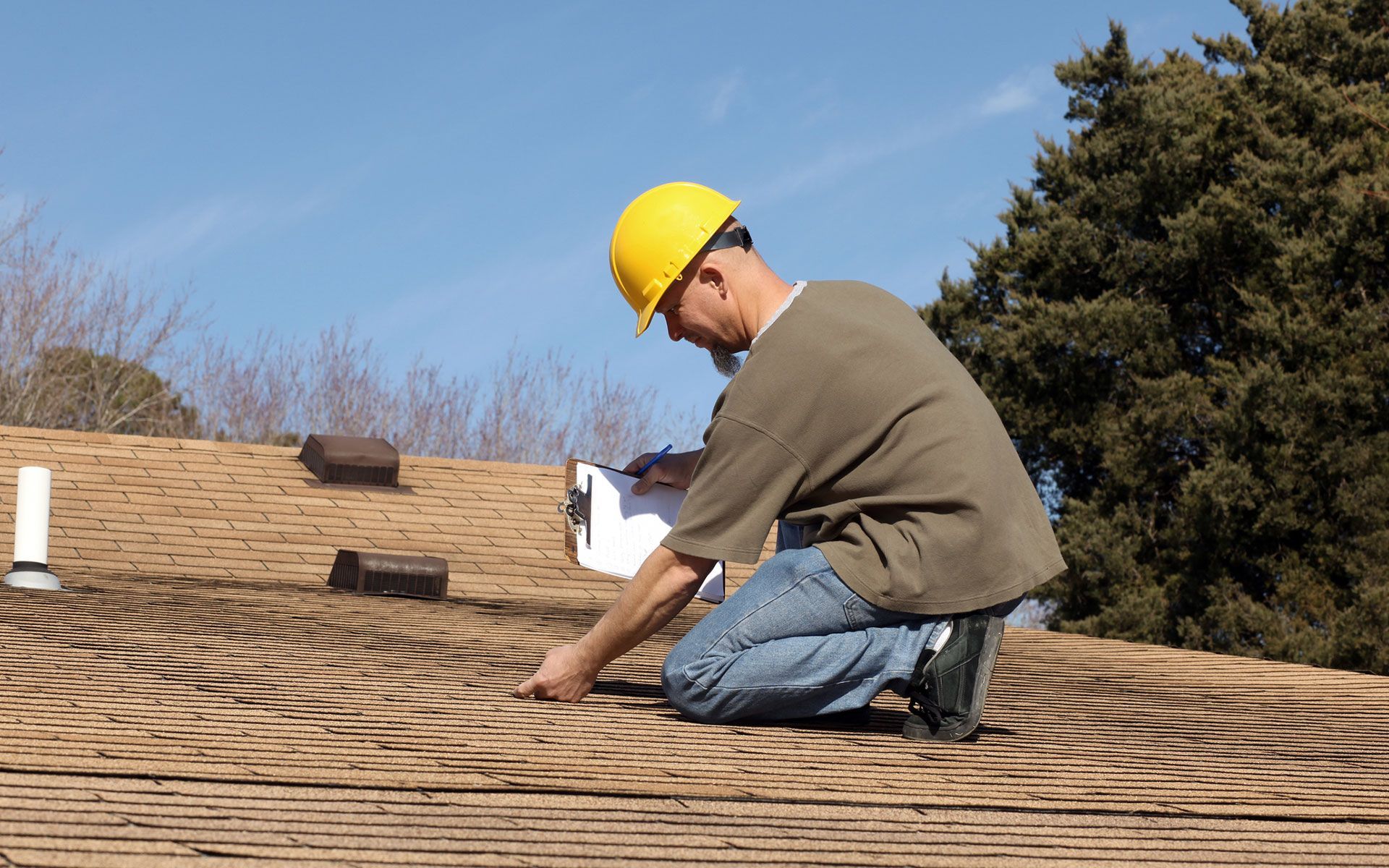 A man wearing a hard hat is working on a roof