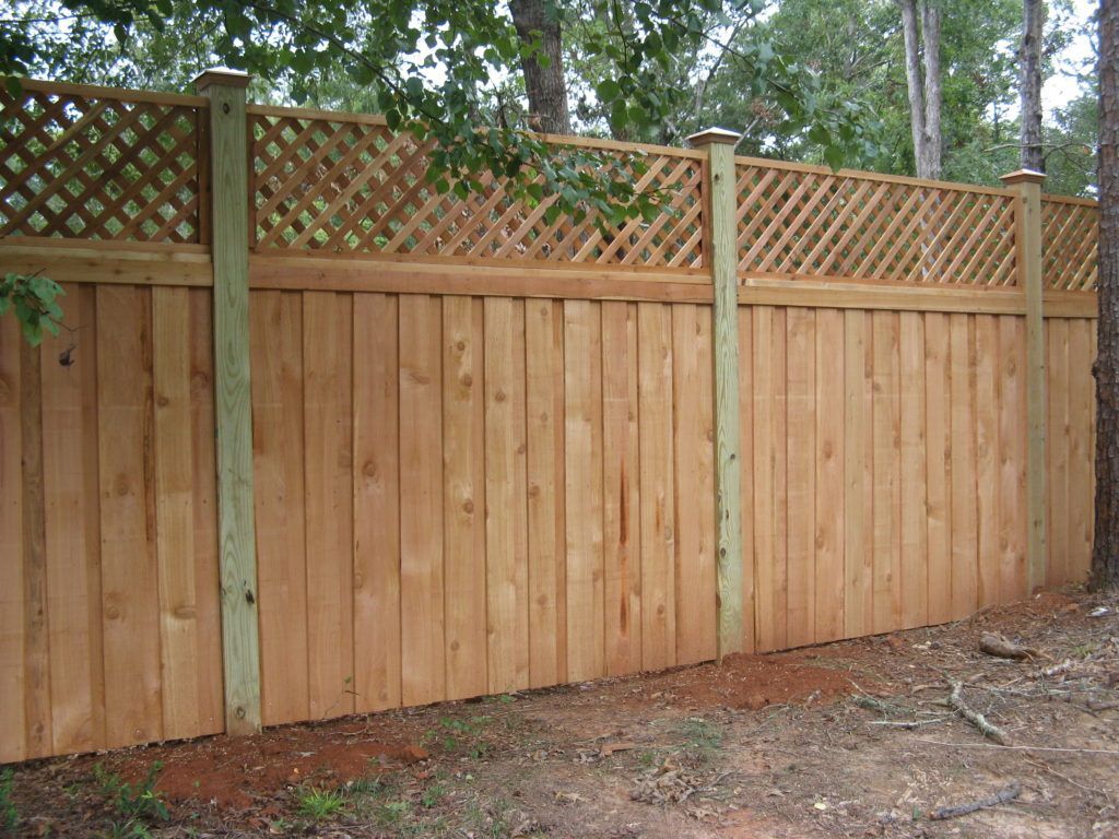Wooden privacy fence with lattice top in a wooded yard