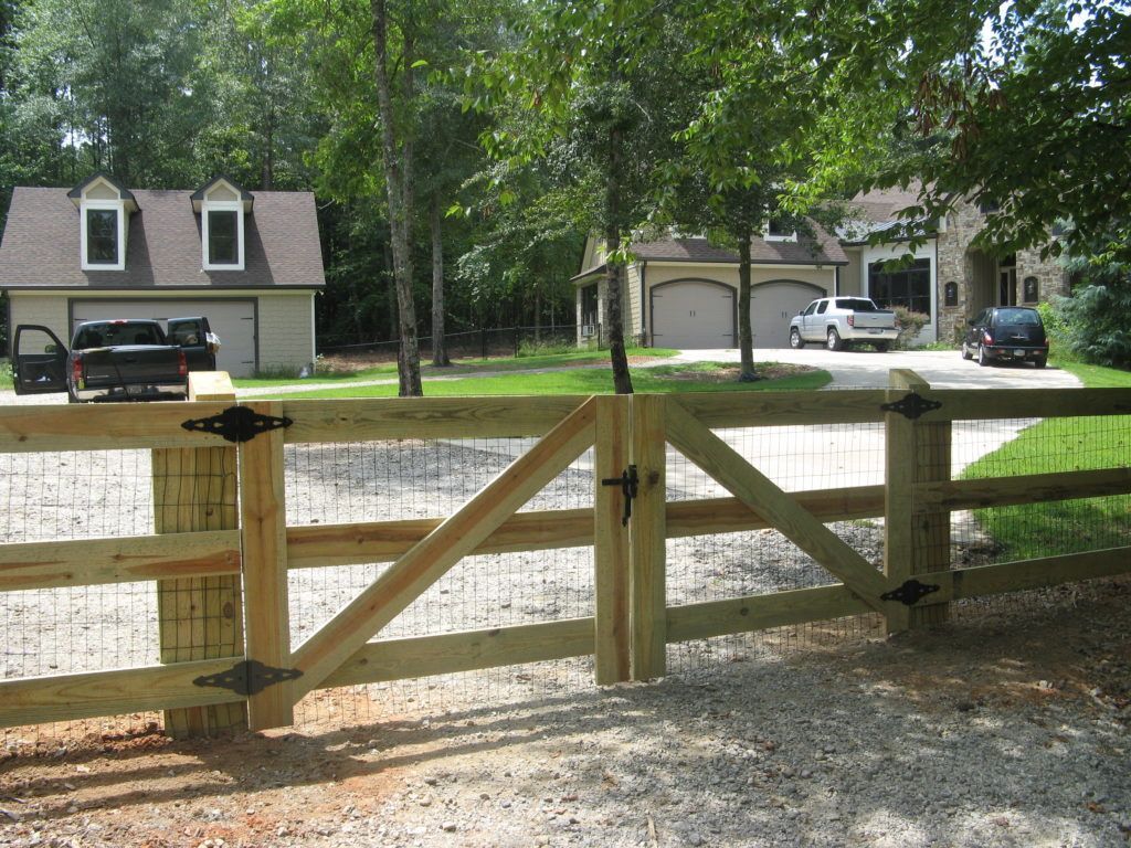 Wooden fence gate beside a quiet suburban street with houses and parked cars.