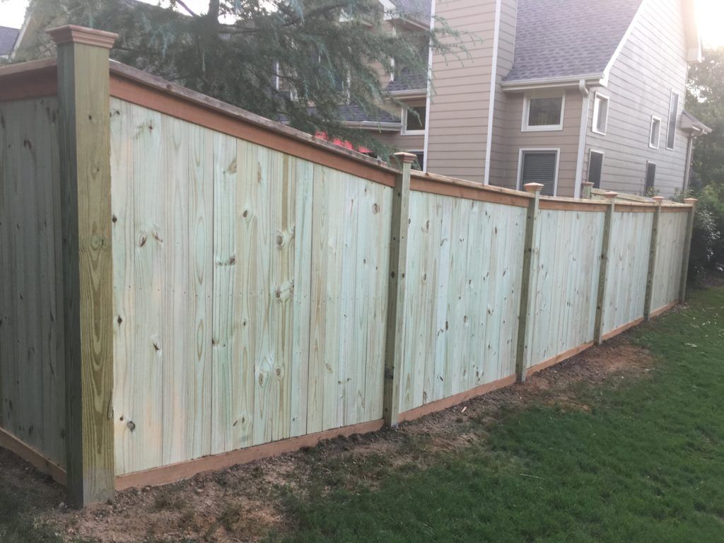 Freshly built light green wooden privacy fence along a grassy yard beside a house