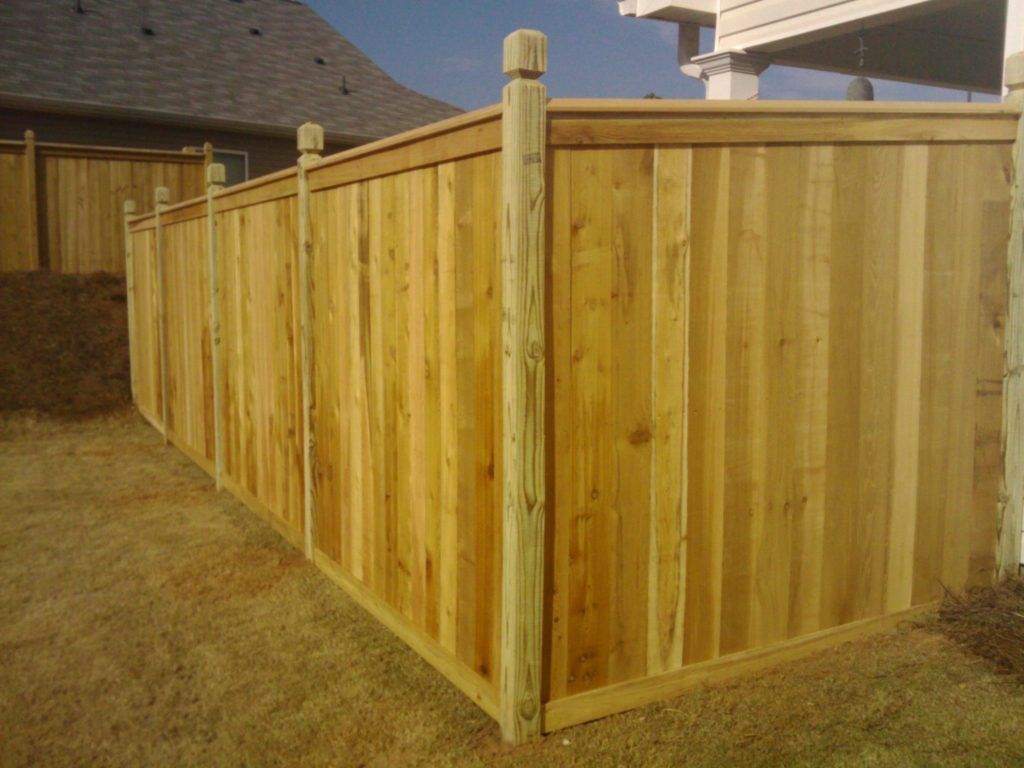Wooden privacy fence enclosing a backyard corner on dry grass under sunlight