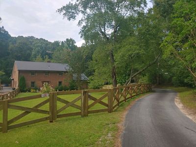 Wooden fence in a rural field with trees and a blue sky with clouds in the background