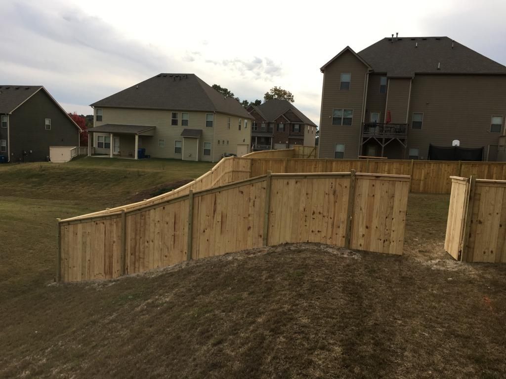 Wooden fence enclosing a grassy yard in a suburban neighborhood under overcast skies