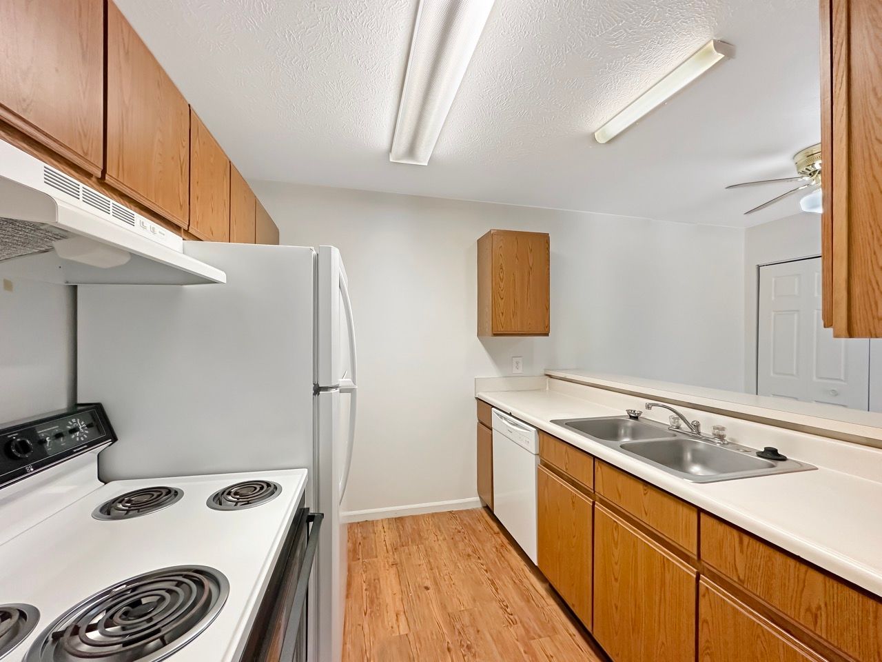 A kitchen with a stove , refrigerator , sink and cabinets.