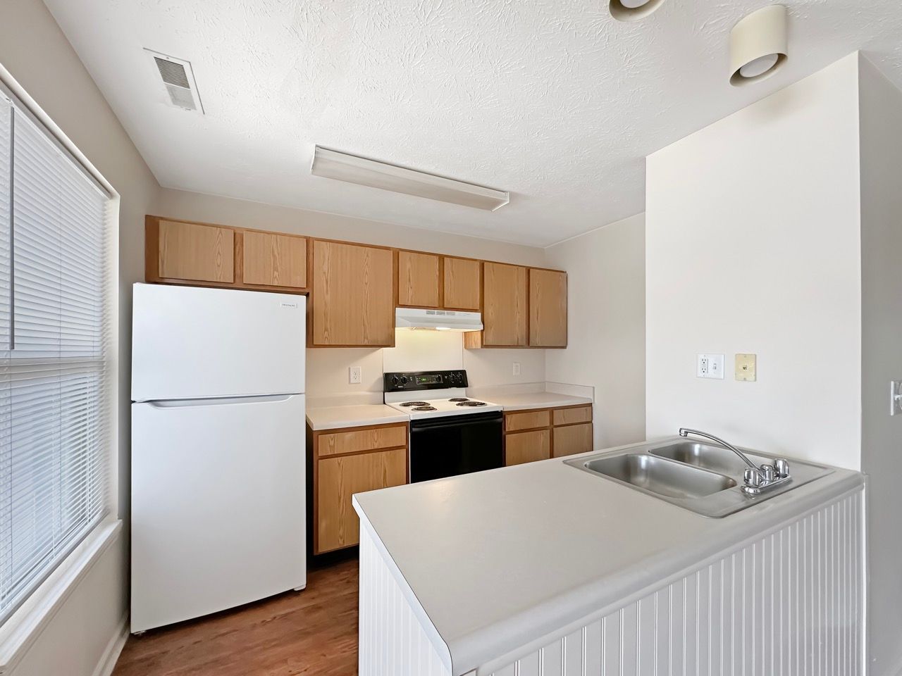 A kitchen with a white refrigerator stove and sink