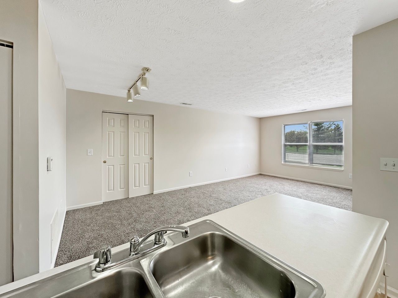 A kitchen with a sink and a living room in the background.