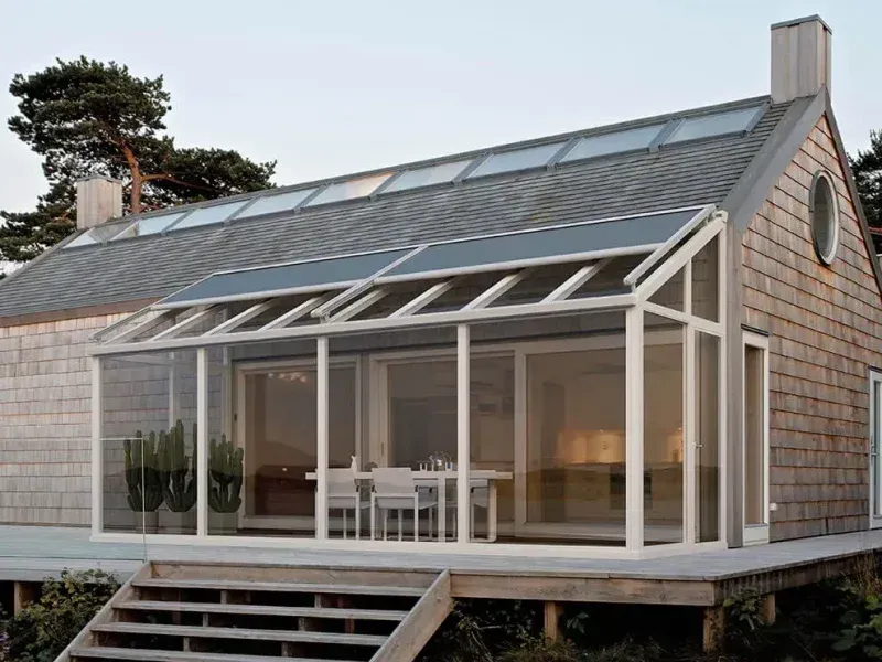 Casa moderna con veranda vetrata e scalini in legno al crepuscolo