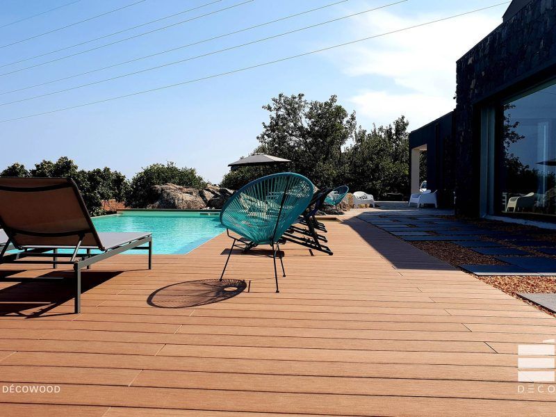 Terrazza esterna con lettini prendisole a bordo piscina color turchese, sotto un cielo azzurro limpido.