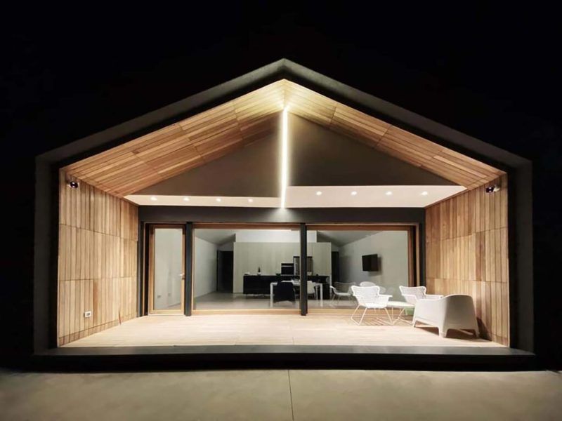 Cabina moderna con facciata in vetro, illuminata di notte da una calda luce interna e arredata in stile minimalista.