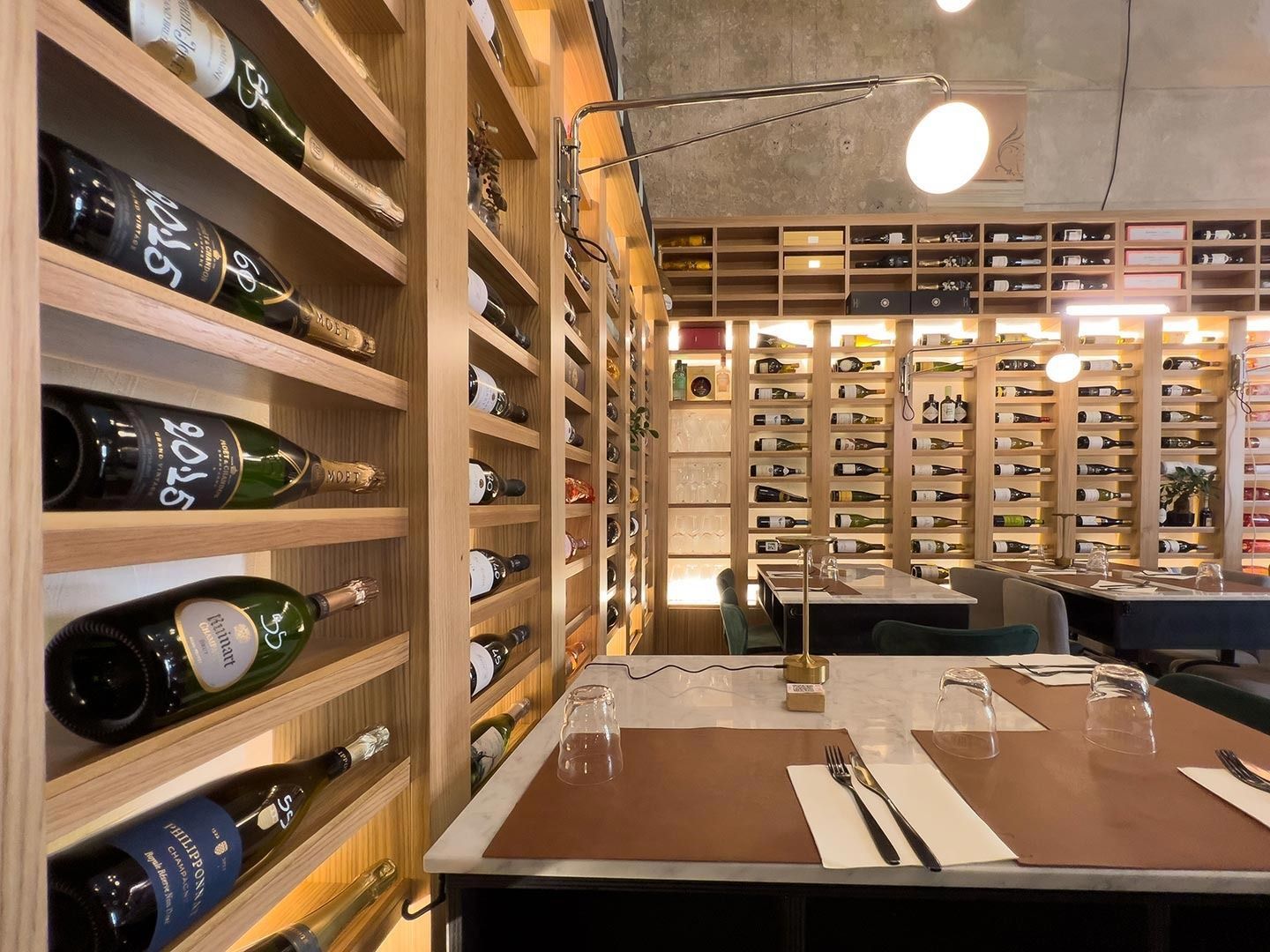 Zona pranzo in cantina con portabottiglie, tavolo apparecchiato e illuminazione calda.