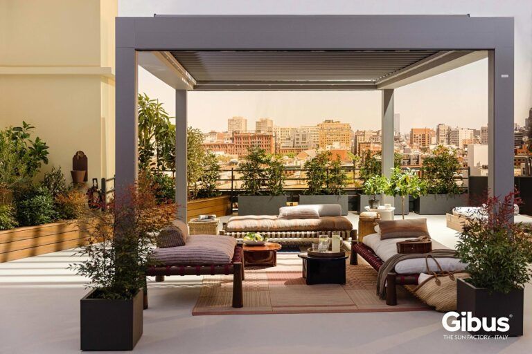 Moderno salotto sul tetto con pergola, divani, piante in vaso e vista sullo skyline della città al tramonto.