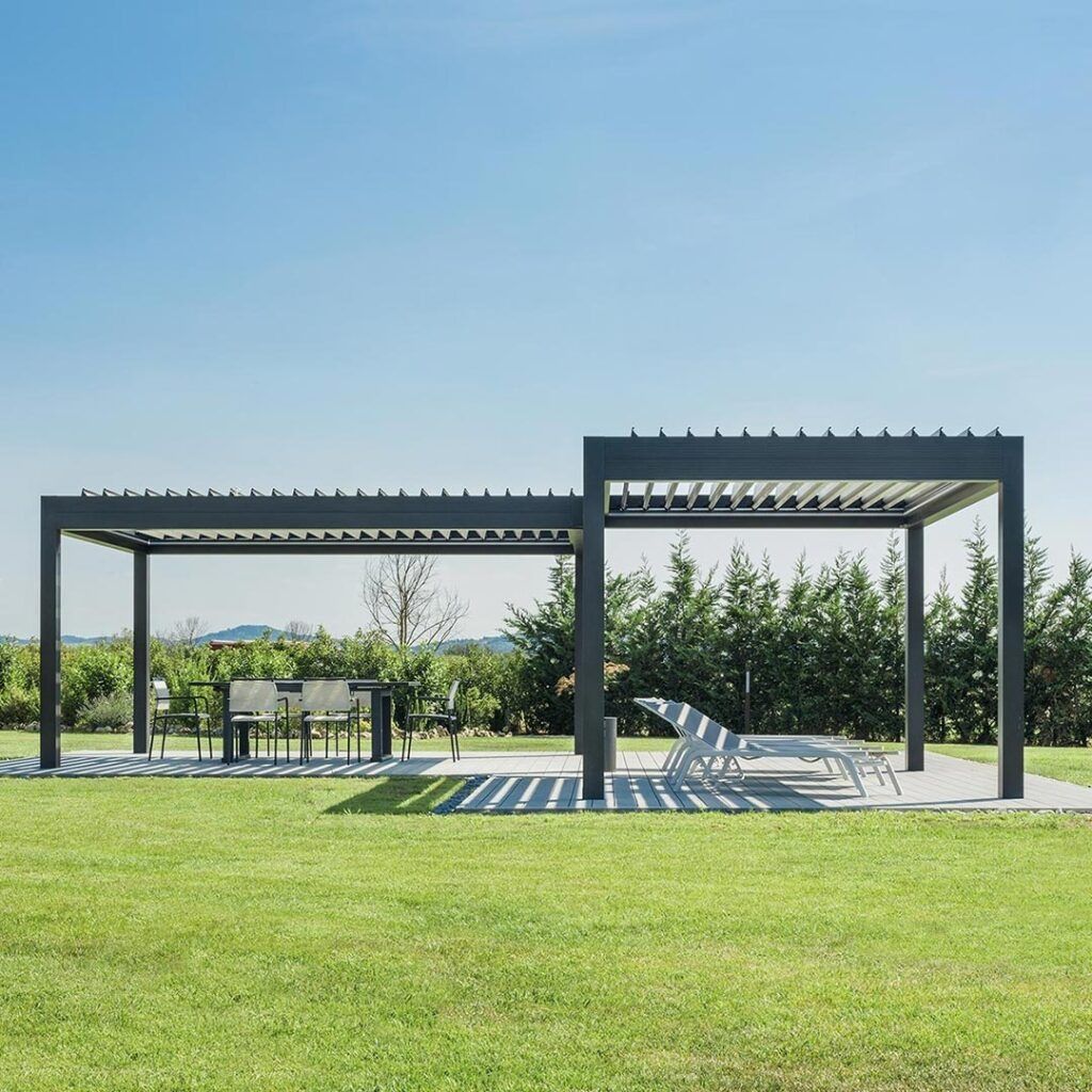 Parco all'aperto con moderne pergole nere e panchine bianche su un prato verde sotto un cielo azzurro.
