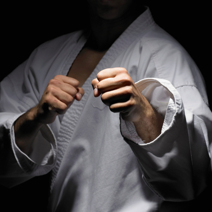 Person in white karate gi with fists clenched, posed in a fighting stance.