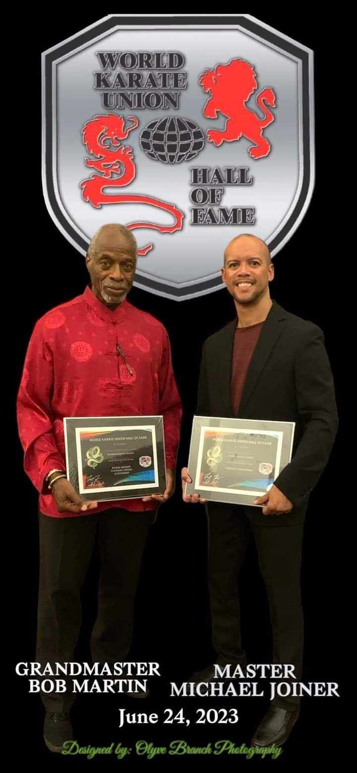Two men with awards under a 