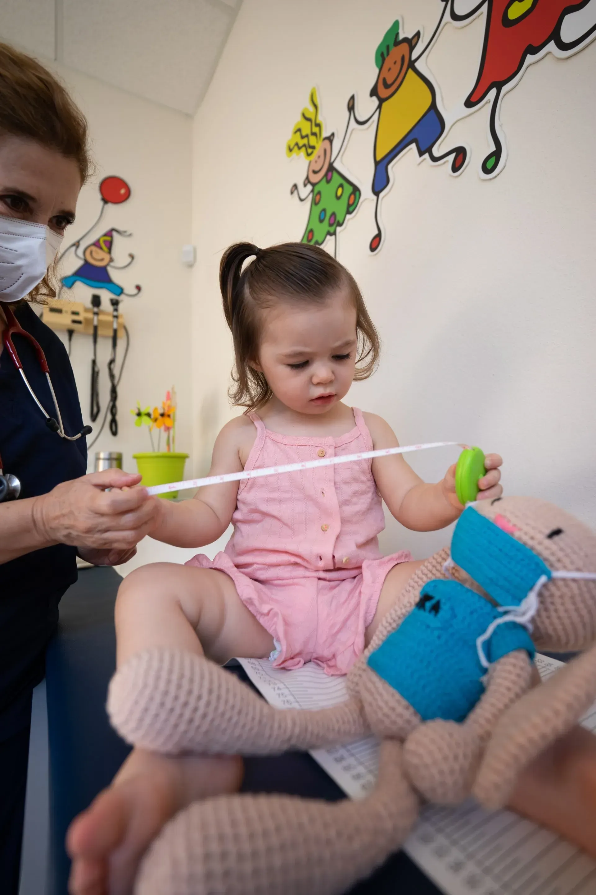 Little girl on medical table holding measuring tape.