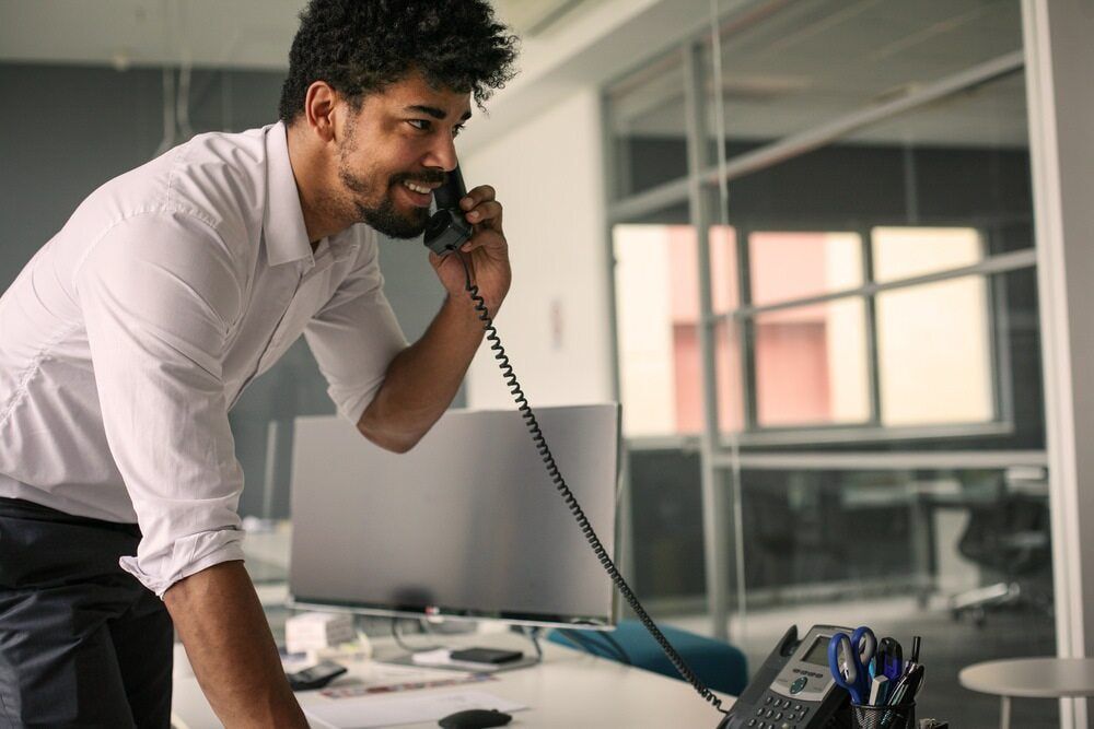 A Man Is Talking On A Telephone In An Office — Black Label I.T. in Garbutt, QLD