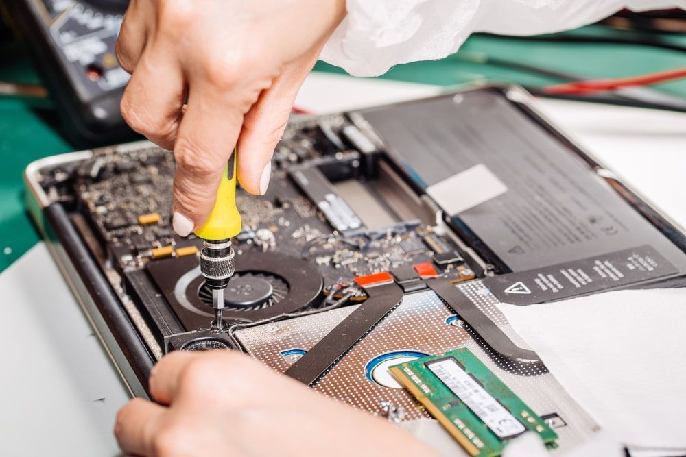 A Person Is Fixing A Laptop Computer With A Screwdriver — Black Label I.T. in Garbutt, QLD