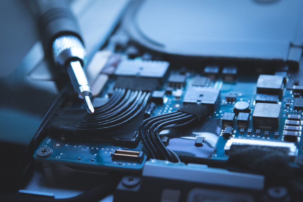 A Close Up Of A Motherboard With A Soldering Iron — Black Label I.T. in Garbutt, QLD