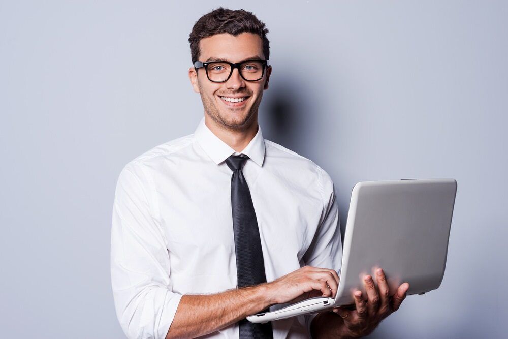 A Man In A White Shirt And Tie Is Holding A Laptop Computer — Black Label I.T. in Garbutt, QLD