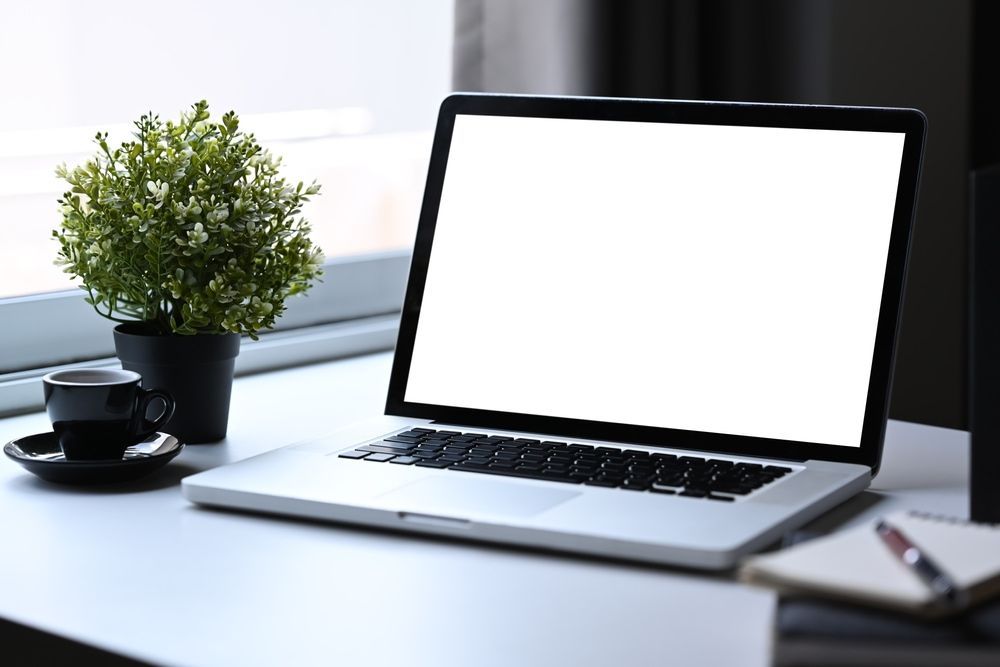 A Laptop Computer Is Sitting On A Desk Next To A Cup Of Coffee And A Potted Plant — Black Label I.T. in Garbutt, QLD