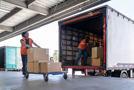Workers loading boxes into a delivery truck in a warehouse loading bay