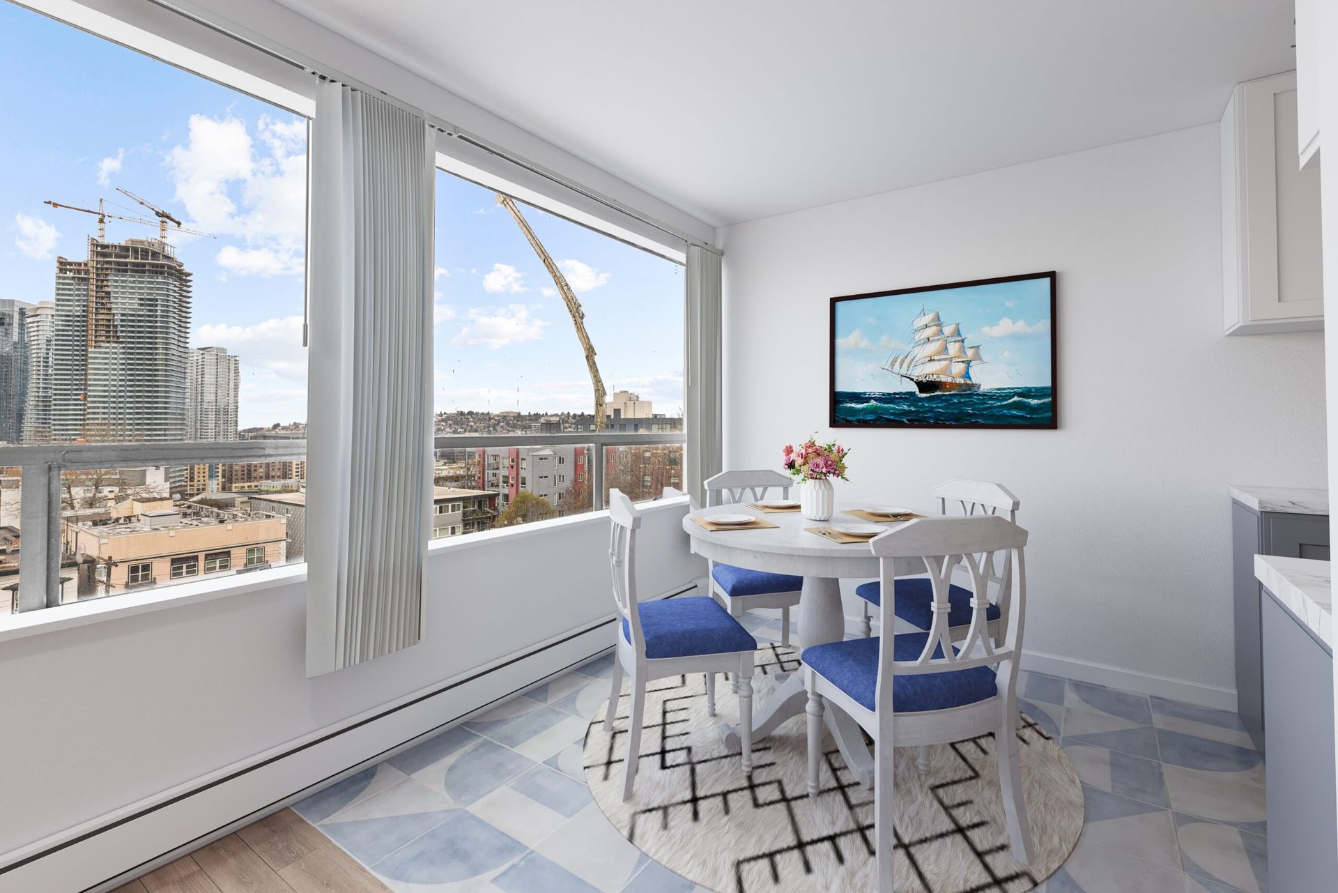 Dining room with a round table, blue chairs, large windows, and cityscape view.