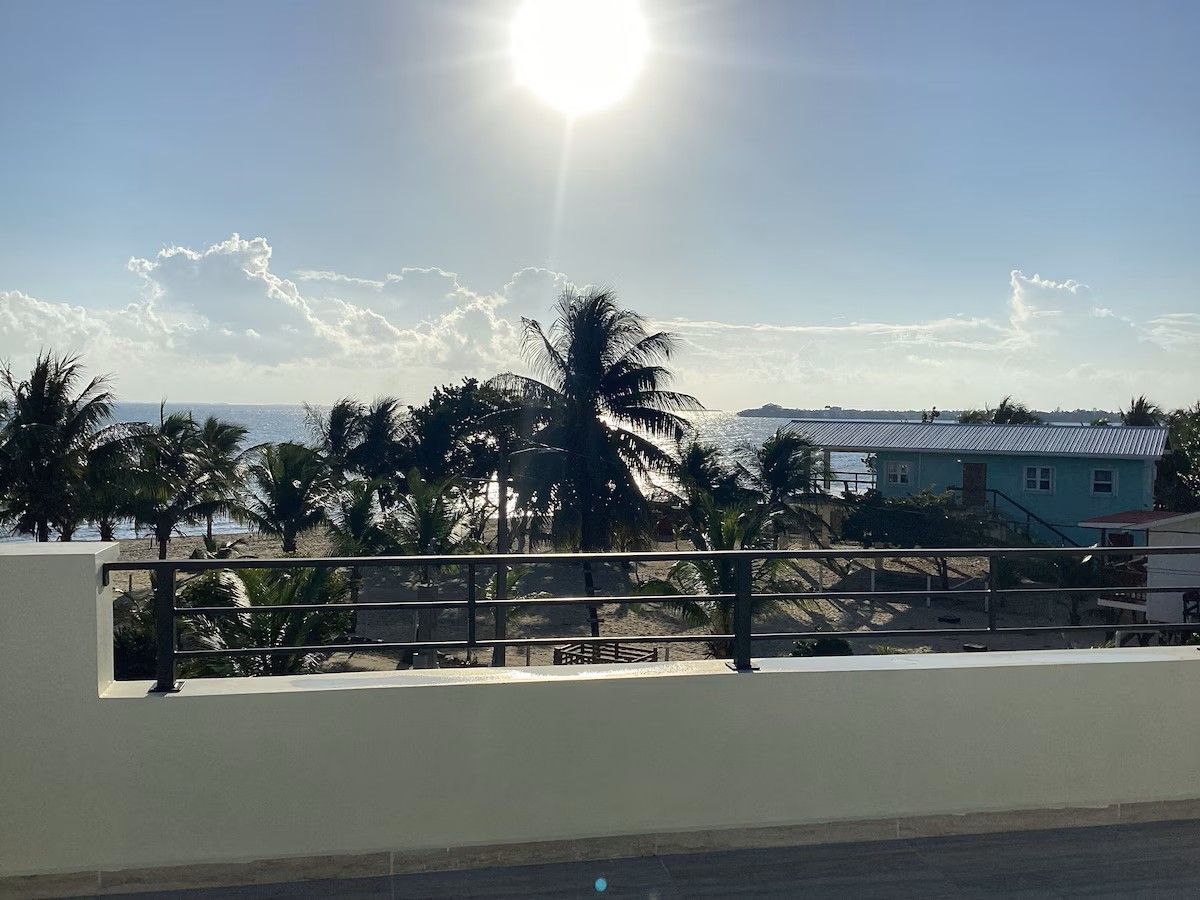A balcony with a view of the ocean and palm trees from Paradise Inn Placencia